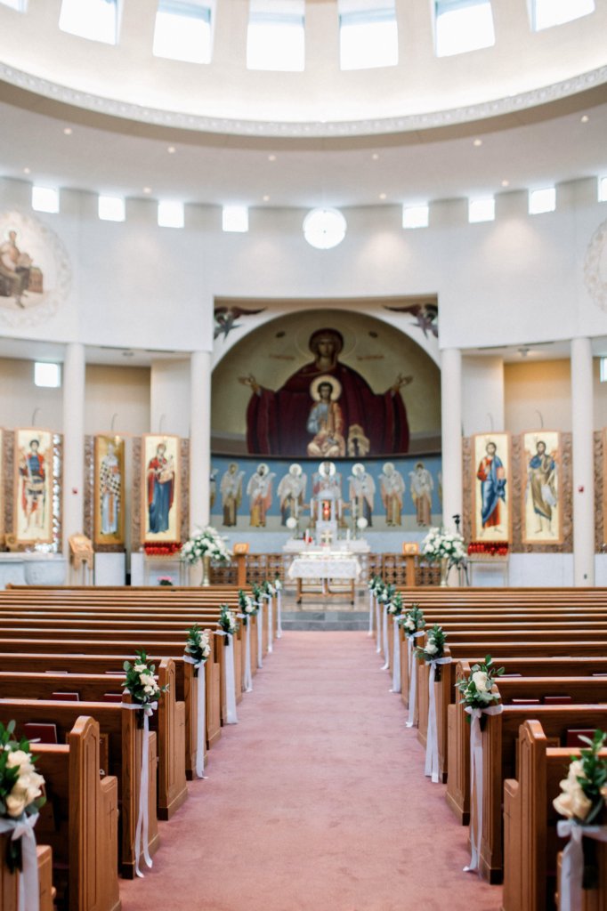 Church wedding ceremony aisle with white rose pew florals and ribbon by Let's Bloom Florist