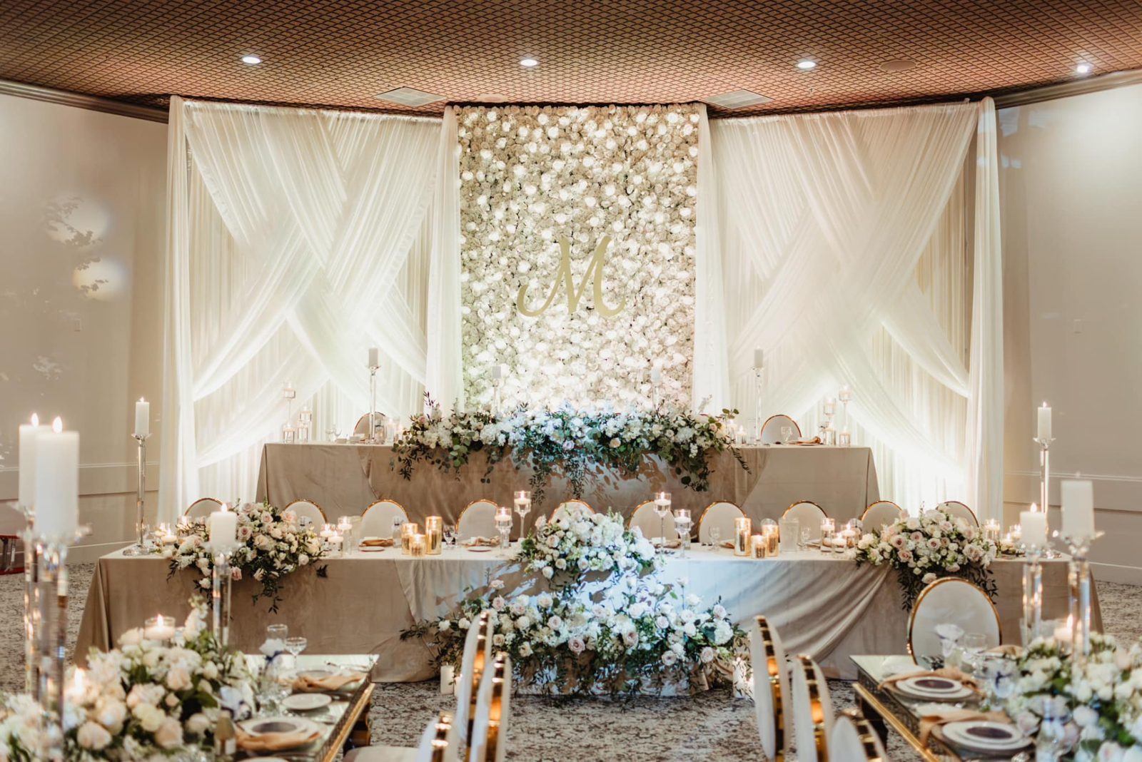 Let's Bloom Florist sheer white ceiling draping behind a floral wall and head table