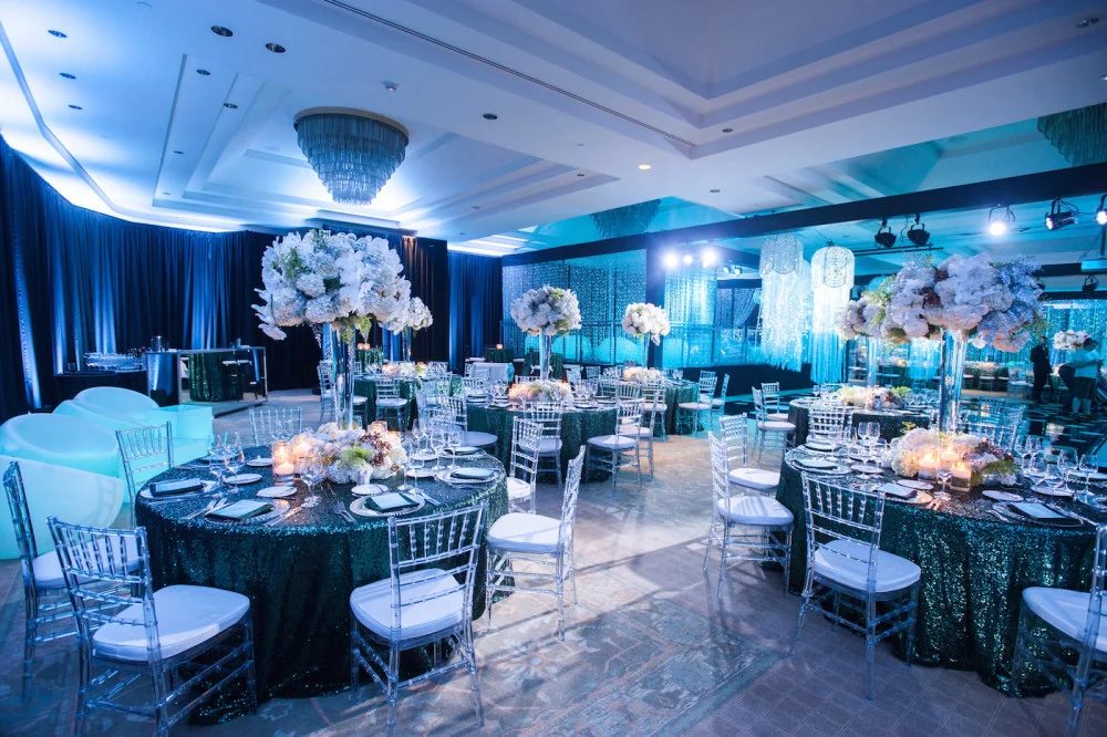 Let's Bloom Florist bat mitzvah ballroom with teal lighting, sequin linens and tall white centerpieces