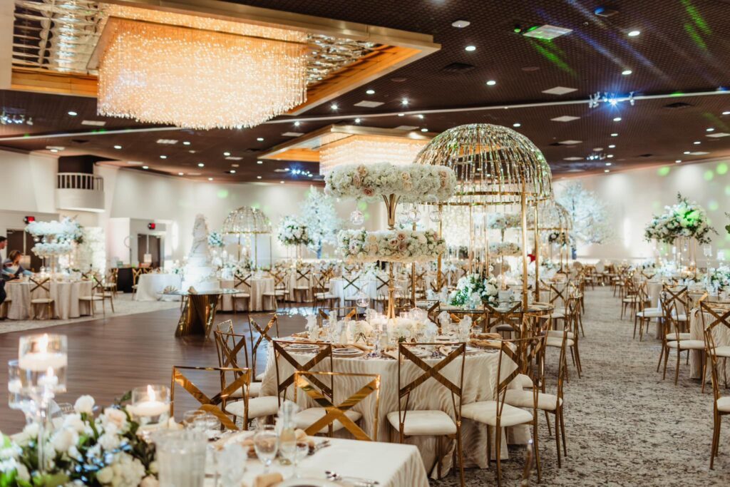 Let's Bloom Florist reception ballroom with tall white and blush centerpieces, gold chairs and crystal chandeliers