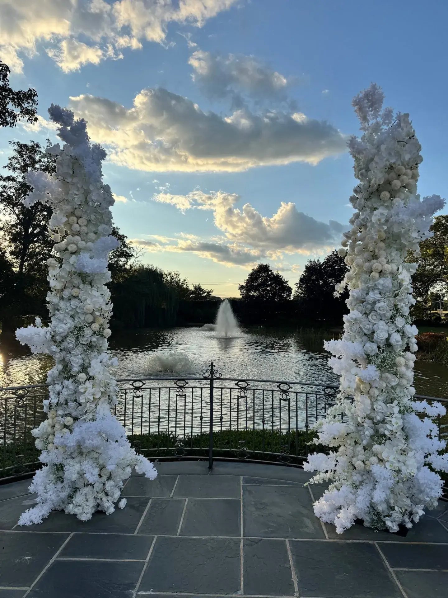 White floral columns framing the lake fountain at sunset at Park Chateau, NJ, by Let's Bloom Florist