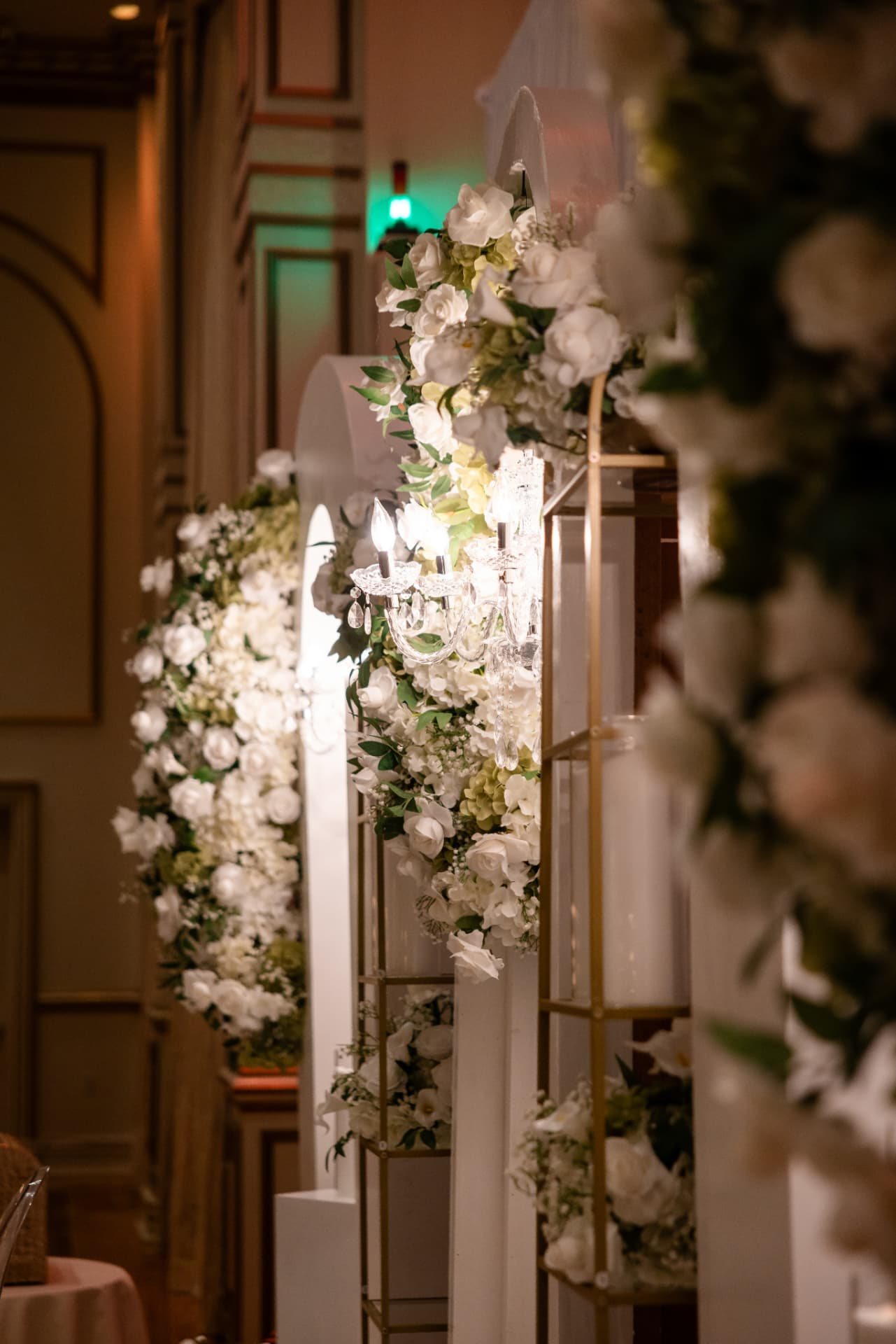 Arch Detail · Crystal Sconce Lit Inside a Flower-Framed White Arch Beside Gold Candle Shelves — The Tides Estate · North Haledon, NJ, by Let's Bloom Florist