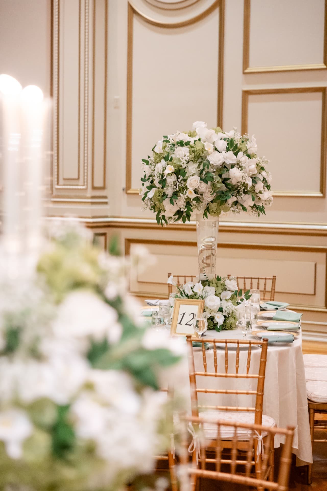 Table 12 · Gold-Framed Table Number Beneath a Tall White and Green Arrangement — The Tides Estate · North Haledon, NJ, by Let's Bloom Florist
